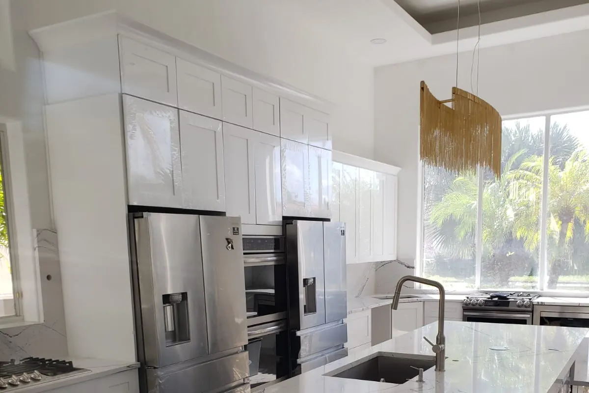 Luxury kitchen cabinet install with calacatta marble island, navy painted base cabinetry and tropical Florida view — South Blue Enterprises kitchen install in Deerfield Beach, FL